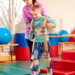 Pediatric physiotherapist guiding a child wearing TheraTogs to improve posture and gait during therapy session